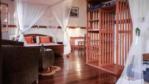 a bedroom with a bed and a room with a wooden floor at Hotel Ambalakely in Ambalakely