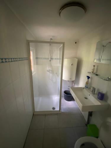 a white bathroom with a shower and a sink at Chalet in Lanaken