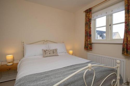 a white bed in a room with a window at Cosy coach house in historical Tetbury in Tetbury