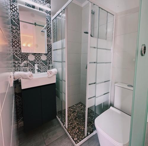 uma casa de banho com um WC e uma cabina de duche em vidro. em bhc Boutique Hostal Cala Millor em Cala Millor