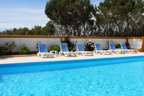 a row of lounge chairs next to a swimming pool at Casa de Campo Sao Rafael - Turismo Rural in Óbidos