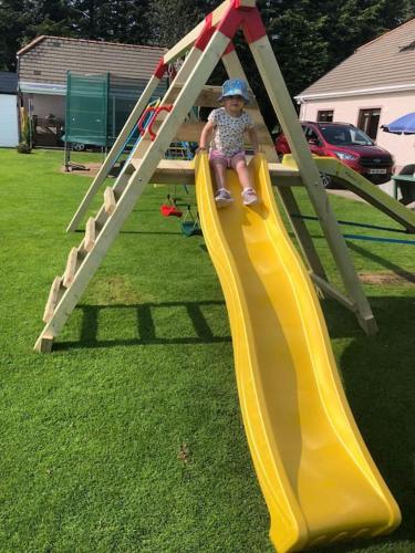 a little girl riding on a slide on a playground at Meadow House in County Donegal in Donegal