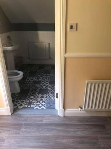 a bathroom with a toilet and a tile floor at Meadow House in County Donegal in Donegal
