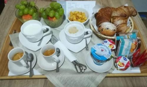 a tray with cups and saucers and a tray of breakfast food at A Suata in Maratea