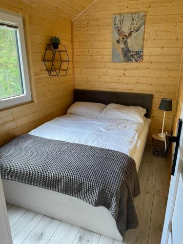 a bedroom with a bed in a wooden cabin at Domek Wakacyjny Myśliborka 2 in Myślibórz Wielki