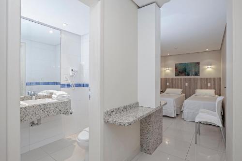 a bathroom with two sinks and a toilet and a mirror at Slaviero Ingleses Convention in Florianópolis
