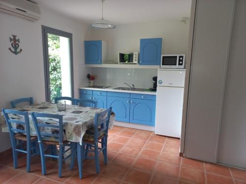 cocina con armarios azules, mesa y sillas en Mazet Provençal dans Village Vacances, en Gaujac
