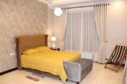 a bedroom with a yellow bed and a chair at Villa Munjul Indah - Majalengka in Jatipamor