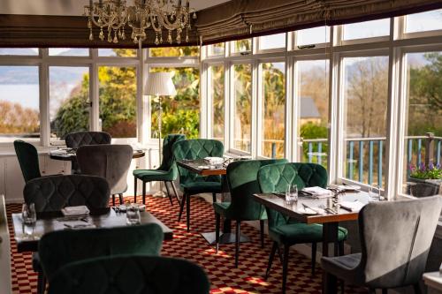 a restaurant with tables and chairs and windows at Duisdale House Hotel in Isleornsay