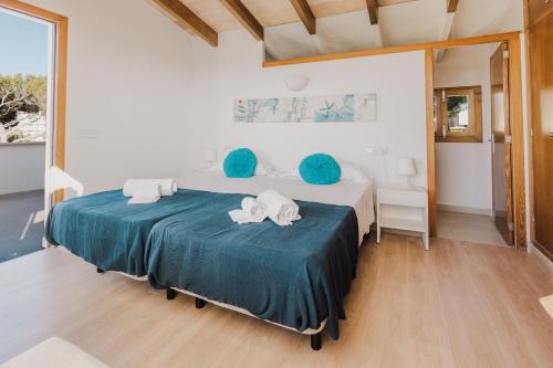 a bedroom with a large bed with blue cushions at Sa Punta Dúplex Cala Ratjada in Cala Ratjada