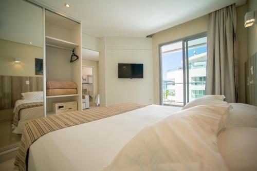 a bedroom with a large white bed and a window at Slaviero Ingleses Convention in Florianópolis