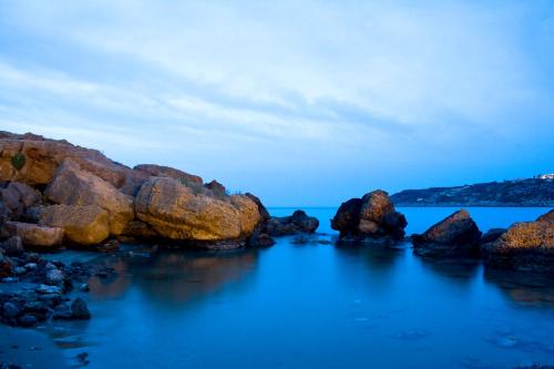 a group of rocks in the water at dusk at Sia's Sea House in Almirida