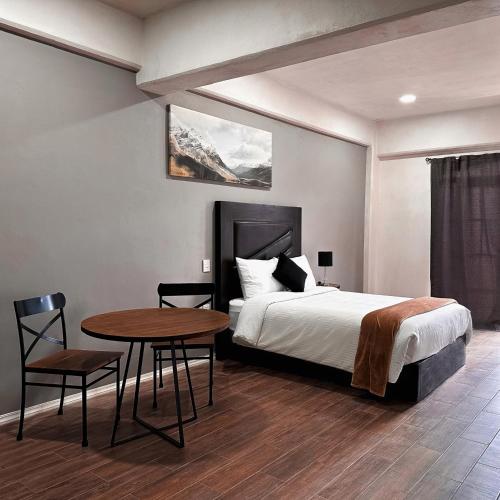 a bedroom with a bed and a table and chair at Hotel Santa María in Taxco de Alarcón