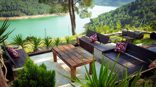 a patio with benches and a table and a lake at Casa Rural Los Parrales in El Tranco