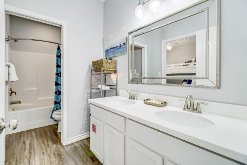 a white bathroom with a sink and a mirror at Carpe BeachBum in Port Aransas