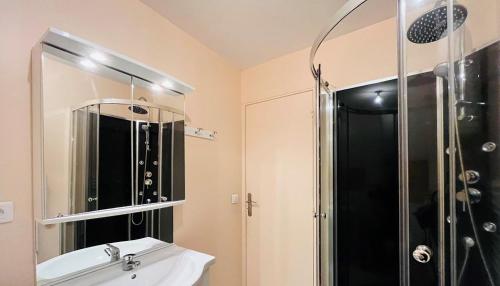 Un baño con ducha, lavabo y espejo. en Le doux refuge, en Le Mont-Dore