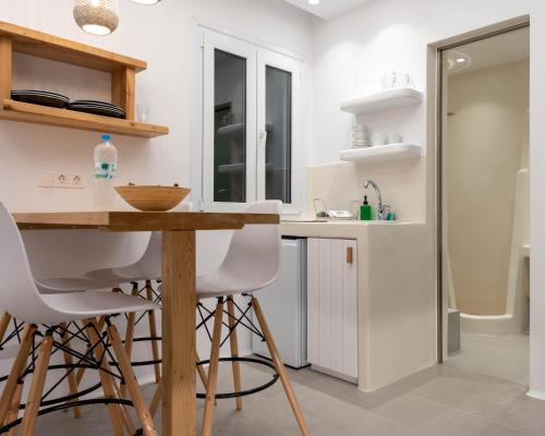 una cocina con armarios blancos, mesa de madera y taburetes en Dedalos Studios Naxos en Naxos