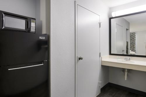 a bathroom with a black refrigerator and a sink at Suburban Studios in Hinesville