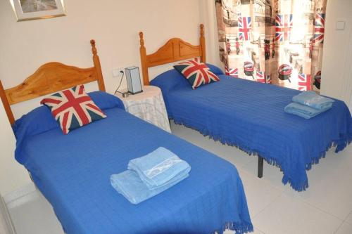 deux lits dans une chambre avec des draps bleus et des serviettes britanniques dans l'établissement Duplex junto al Mar con Jardin y Piscina, à Puerto de Mazarrón