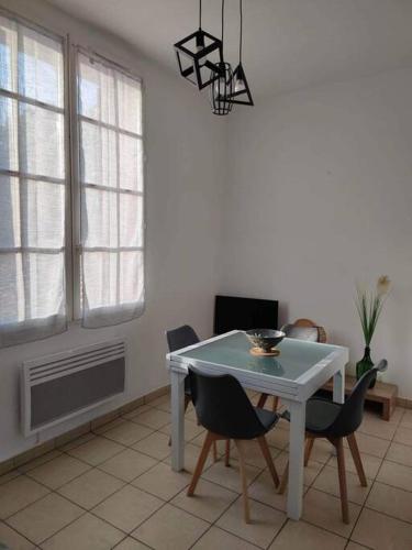 une salle à manger avec une table et des chaises blanches dans l'établissement Arcachon Appartement 4 personnes - Résidence Beauséjour, à Arcachon