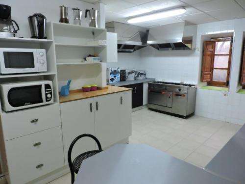a kitchen with white cabinets and a table and a microwave at Casa Rural Los Parrales in El Tranco