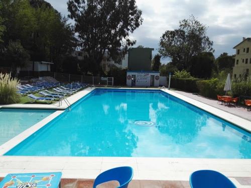een groot blauw zwembad met blauwe stoelen in een tuin bij Playa de Aro in Platja  d'Aro