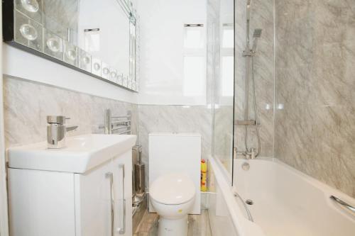 a bathroom with a toilet and a sink and a bath tub at Cozy 2BR Flat Central London Sleeps 3 in London