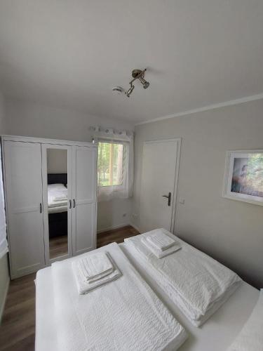 a white bedroom with a bed and a cabinet at Ferienbungalows am Wolziger See in Heidesee
