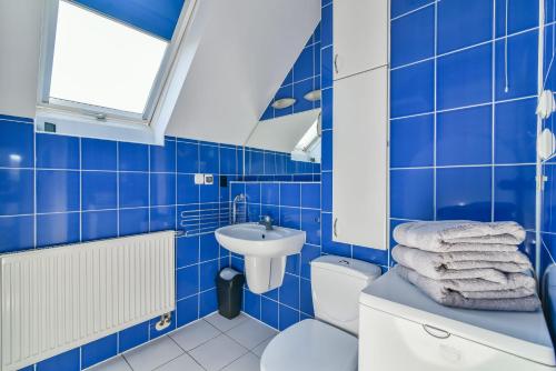 a blue tiled bathroom with a toilet and a sink at Apartament Morski Rewa in Rewa