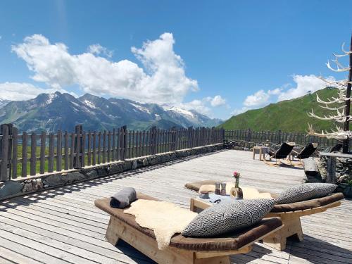 a wooden deck with a table and chairs and mountains at Schneekarhütte in Mayrhofen