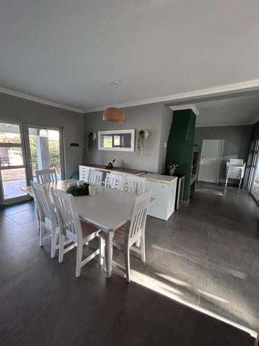 a kitchen and dining room with a white table and chairs at Blisss in Boggomsbaai