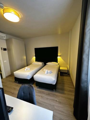a room with two beds and a desk and a table at PFA Hotel Ginevra - Isola d'Elba in Cavo