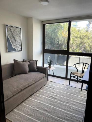 a living room with a couch and a large window at AT HOME El Golf in Santiago