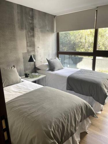 two beds in a room with a window at AT HOME El Golf in Santiago