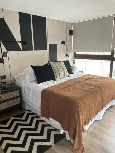 a bedroom with a large bed with a brown blanket at AT HOME El Golf in Santiago