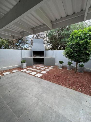 a concrete patio with a fireplace in a backyard at Blisss in Boggomsbaai
