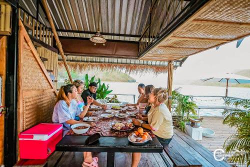 un grupo de personas sentadas en una mesa comiendo comida en Hometown Riverview - โฮมทาวน์ ริเวอร์วิว, en Si Sawat