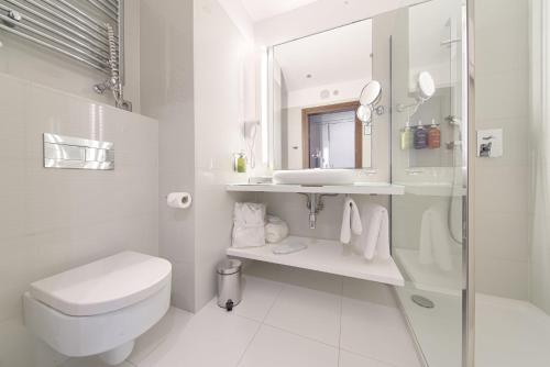 a white bathroom with a toilet and a sink at Qubus Hotel Bydgoszcz in Bydgoszcz