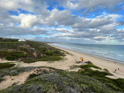 a beach with people walking on the sand and the ocean at Blisss in Boggomsbaai