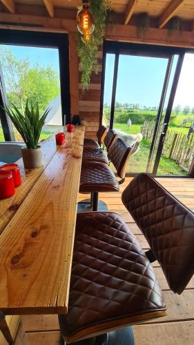 a wooden table and chairs in a room with windows at De luxe overkapping in Middelburg