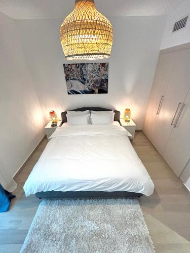 a bedroom with a large white bed with a chandelier at The Hive Retreats in Yas Island in Abu Dhabi