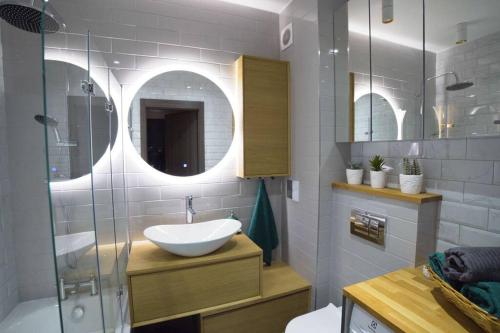 a bathroom with a sink and a glass shower at Nowoczesny dwupokojowy Apartament Bridget z parkingiem in Ełk