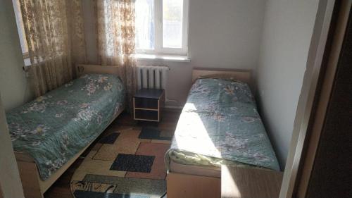 a small room with two beds and a window at Hostel A99 in Astana