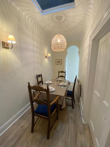 Peaceful Coastal Apartment في فنتنور: غرفة طعام مع طاولة وكراسي وثريا