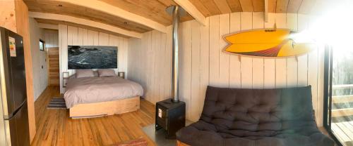 ein Schlafzimmer mit einem Bett und einem Stuhl in einem Zimmer in der Unterkunft Cabañas La Ola Puertecillo in Navidad