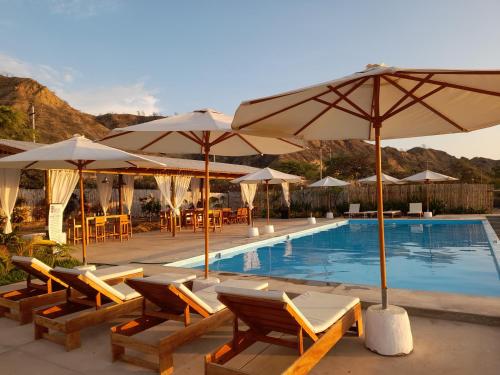 a swimming pool with chairs and umbrellas next to a pool at El Delfin in Zorritos