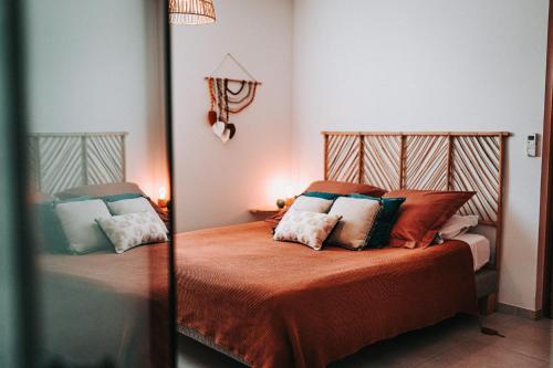 Un dormitorio con una cama con almohadas. en Maloé Lodge T2 (2 min à pieds plage et surf), en Sainte-Anne