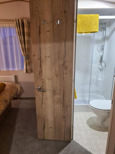 a bathroom with a wooden door and a toilet at Haggerston Castle , Cheviot View in Cheswick