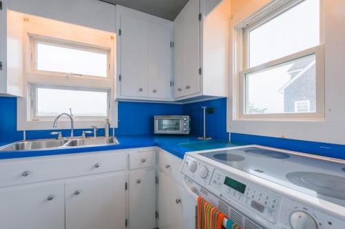 una cocina con armarios blancos y paredes y ventanas azules. en 80 Salt Marsh Road East Sandwich - Cape Cod, en East Sandwich