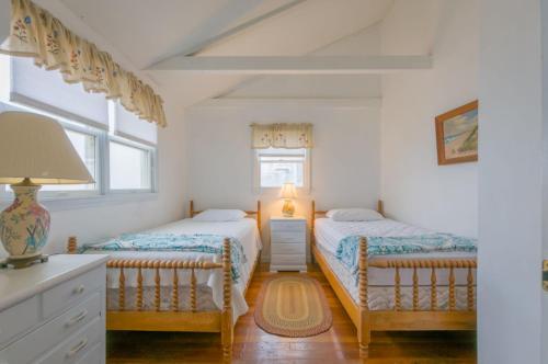 2 camas en un dormitorio con paredes y ventanas blancas en 80 Salt Marsh Road East Sandwich - Cape Cod, en East Sandwich